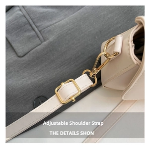 Detail view of the cream leather adjustable shoulder strap with light gold metal buckle