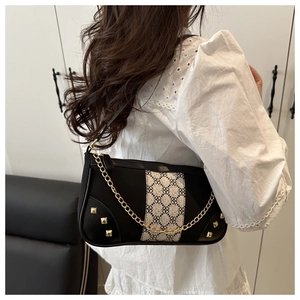 Detail of black underarm bag with white geometric print and gold chain hardware decoration