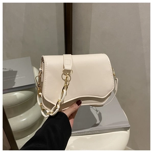 Detail of cream crossbody bag featuring a wavy flap design and mixed acrylic chain strap