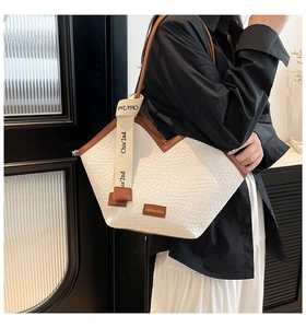 Detail of woven texture tote bag with brown trim and stylish canvas lettered shoulder strap