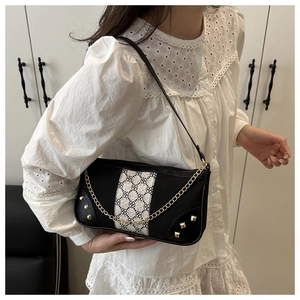 Detail of black baguette shoulder bag featuring gold studs and geometric patchwork design