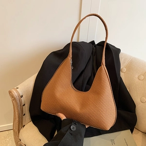 Elegant brown crescent hobo bag with woven texture on a minimalist sofa setting