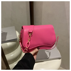 Detail of fuchsia underarm bag with decorative chunky resin and metal chain link straps
