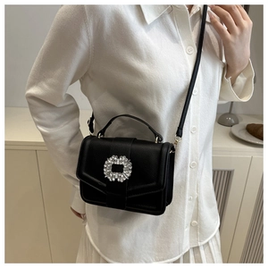 Litchi pattern black handbag with rhinestone buckle shown on model in indoor setting