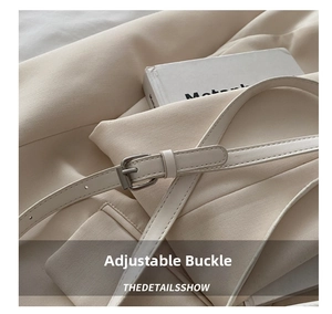 Macro detail of adjustable silver buckle on a creamy white faux leather shoulder bag