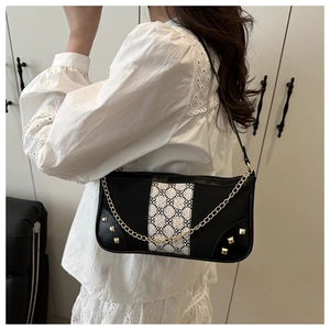 Detail of black baguette bag featuring floral jacquard strap and gold stud accents