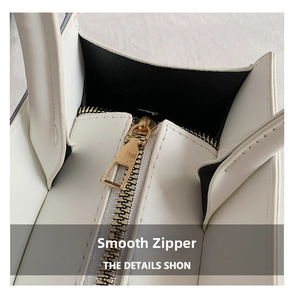 Macro shot of a smooth gold metal zipper on a cream white leather shoulder bag detail