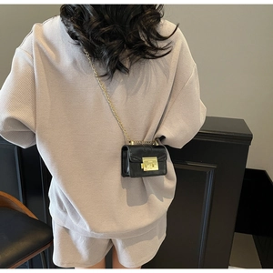 Détail d'un mini sac bandoulière noir avec fermoir doré et bandoulière en chaîne