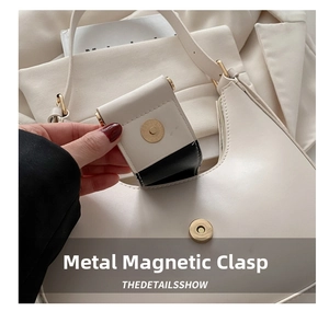 Close-up of golden magnetic buckle on cream leather shoulder bag with hand opening it