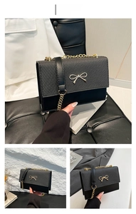 Detailed view of black crossbody bag with golden bow clasp and chain strap textures
