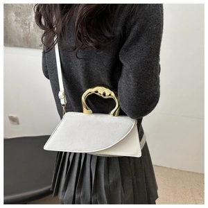 Detail of white leather mini square bag with a chunky gold-tone artistic handle and thin strap