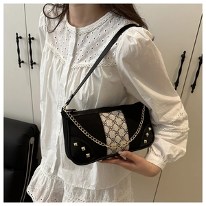 Detail of vintage black leather bag with jacquard fabric, gold studs, and metal chain
