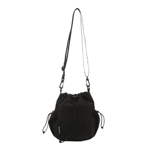 Minimalist black drawstring bucket shoulder bag with mesh pockets and fashion tag
