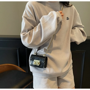 Détail de la texture gaufre gris clair avec mini sac à chaîne porté par le modèle