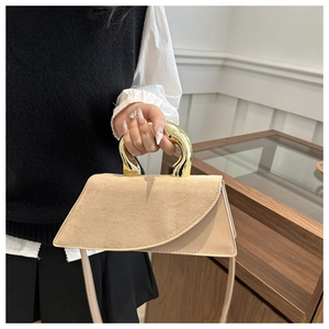 Detailed close-up of a khaki suede and matte leather handbag with a gold metal handle