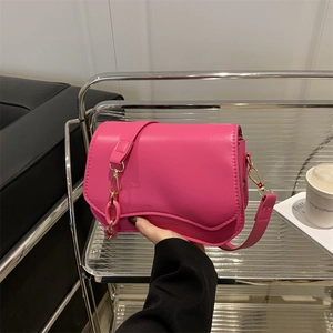 Barbie pink shoulder bag with wavy bottom design and gold chain detail in hand