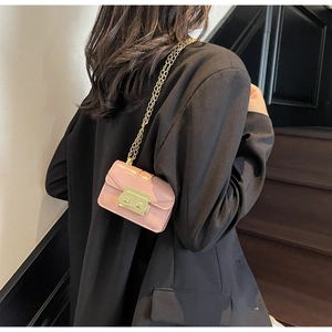 Gros plan sur le mini sac bandoulière rose avec boucle dorée sur une veste noire