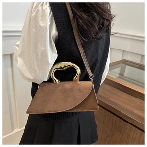 Detail of a brown geometric crossbody bag with gold metal handle and suede texture