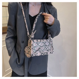 Détail du sac bandoulière rose motif serpent avec bord ondulé et breloque ronde
