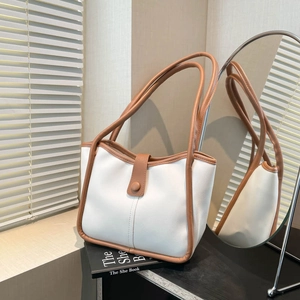Sac seau minimaliste blanc et marron pour le trajet quotidien posé sur des livres