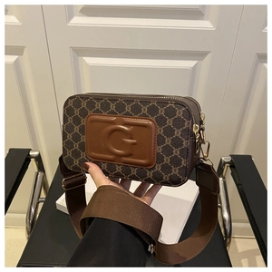 Détail du sac à bandoulière marron à monogramme avec sangle large et écusson logo G gaufré