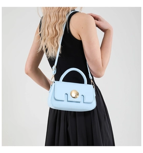 Model wearing a light blue crossbody bag with a gold round buckle and curved handle