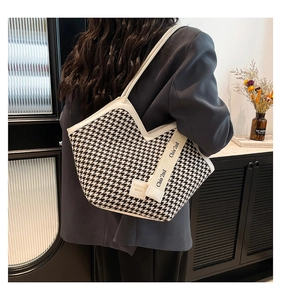 Detail of black and white houndstooth tote bag with white leather straps on shoulder