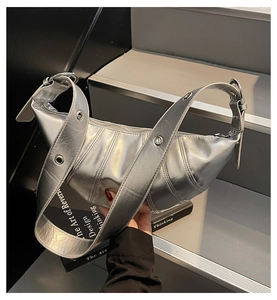 Close-up of silver crescent bag featuring metallic texture and metal grommet strap details