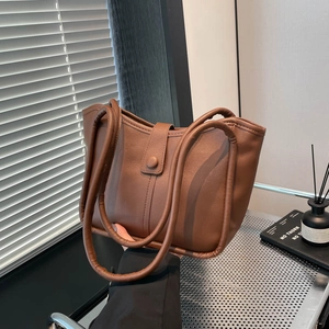 Sac seau en cuir marron grande capacité pour femme présenté dans un cadre d'intérieur