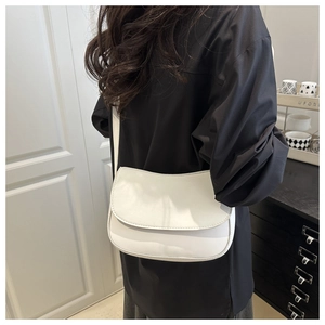Detail shot of white half-moon shoulder bag with flap closure on a model