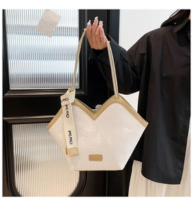 Detail of white crocodile pattern tote bag with V-shaped opening and decorative ribbon