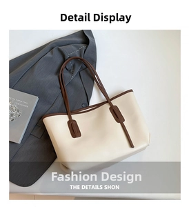 Detail view of cream tote bag with dark brown handles on grey blazer background
