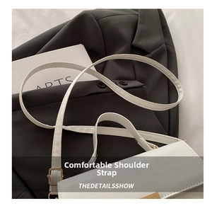 Close-up of adjustable strap and golden hardware on a white leather shoulder bag