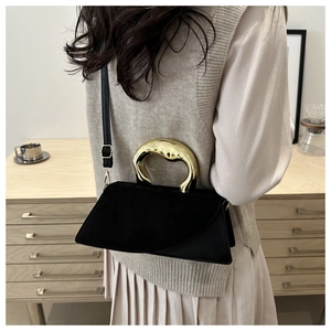 Detail of minimalist black tote bag featuring unique gold flowing metal top handle