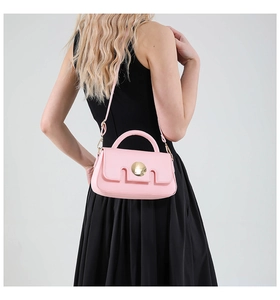 Detailed back view of pink crossbody bag with gold round buckle on black dress