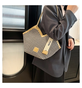 Detail of houndstooth tote bag with brown leather trim and wide graphic strap
