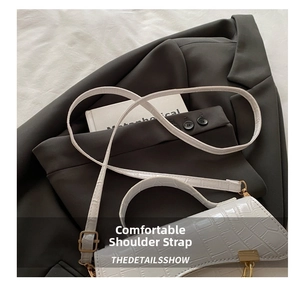 Detail showing the white crocodile pattern handbag with comfortable strap and gold hardware