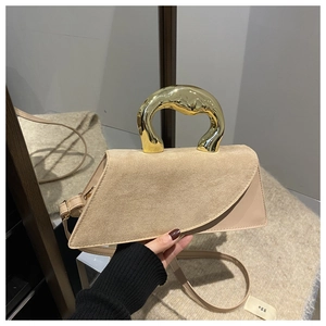 Detail of beige suede and leather bag with an artistic golden metal handle and strap