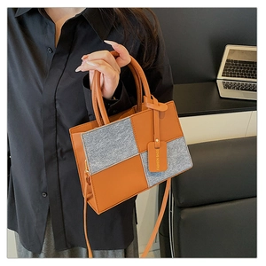 Close-up of the textured gray felt and brown leather patchwork small square handbag