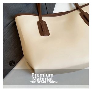 Detail showing high-quality beige leather texture and dark brown contrast handle stitching