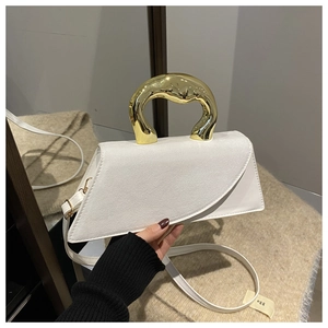 Detail of white asymmetric handbag with gold sculptural handle and suede paneling