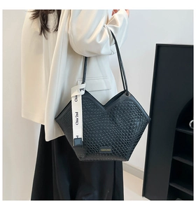 Detail of black woven tote bag featuring unique hexagonal profile and side logo ribbon