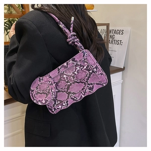 Détail du sac à main violet motif serpent avec base ondulée porté par un mannequin