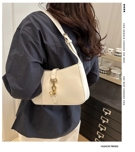 Detail shot of a white PU leather shoulder bag featuring a golden horseshoe buckle