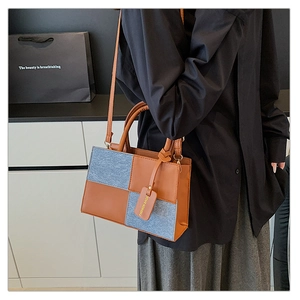 Detail of trendy brown leather and denim patchwork shoulder bag with FASHION BAGS tag