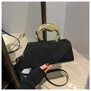 Detail of black suede asymmetrical handbag with a designer gold metallic handle