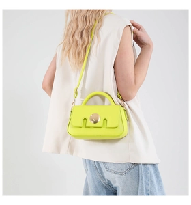 Lime green crossbody bag with gold round buckle shown on model in studio setting