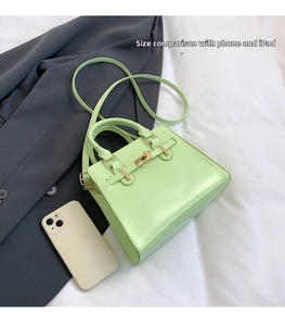 Green leather Kelly bag with golden twist lock and size comparison to a smartphone