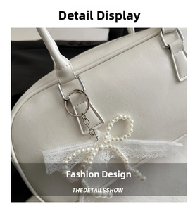 Close-up of white lychee leather texture with pearl bow pendant and silver hardware