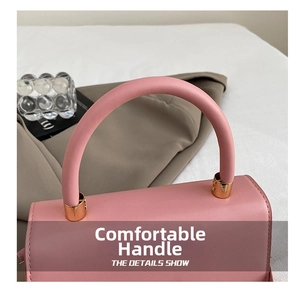 Detail of pink leather handbag with sturdy rounded handle and elegant gold metal hardware